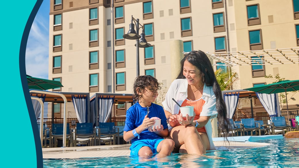 mother and child enjoying sitting by the pool and eating ice cream